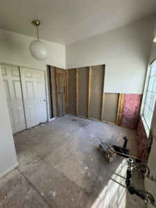 An interior room during a home renovation project with walls removed, exposing studs and insulation by CK Customs LLC in Surprise, AZ.