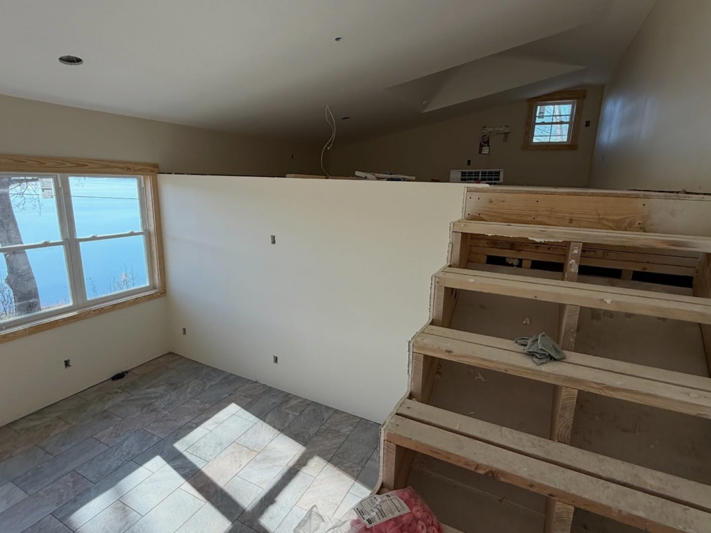 Renovated interior room with unfinished wooden stairs and new drywall by Volunteer Building Services, Knoxville, TN.