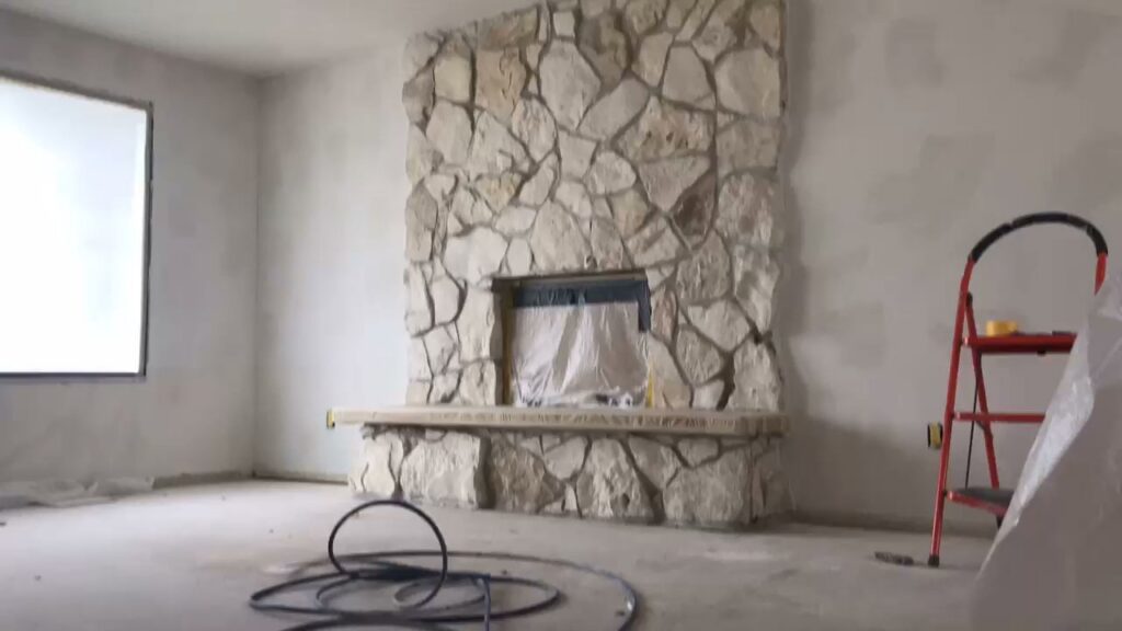 A room undergoing renovation, featuring a stone fireplace and a ladder, indicating painting or drywall work by MDJ Handyman in Salt Lake City, UT.