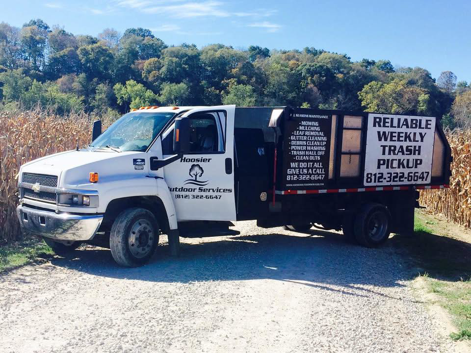 A Hoosier Outdoor Services truck full of junk, including mattresses, ready for removal in Bloomington, IN.