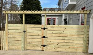 A newly installed horizontal slat wooden fence with a gate and pergola top by Minors Fences in Ashland, VA.