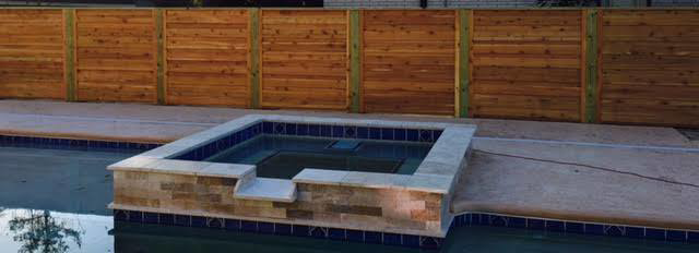 A modern horizontal slat wooden fence installed behind a swimming pool and hot tub by Southern Splendor Fence in Savannah, GA.