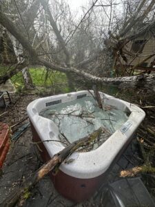 A hot tub covered in fallen tree branches and debris, requiring cleanup services from DeMasters Tree Care LLC in Nampa, ID.