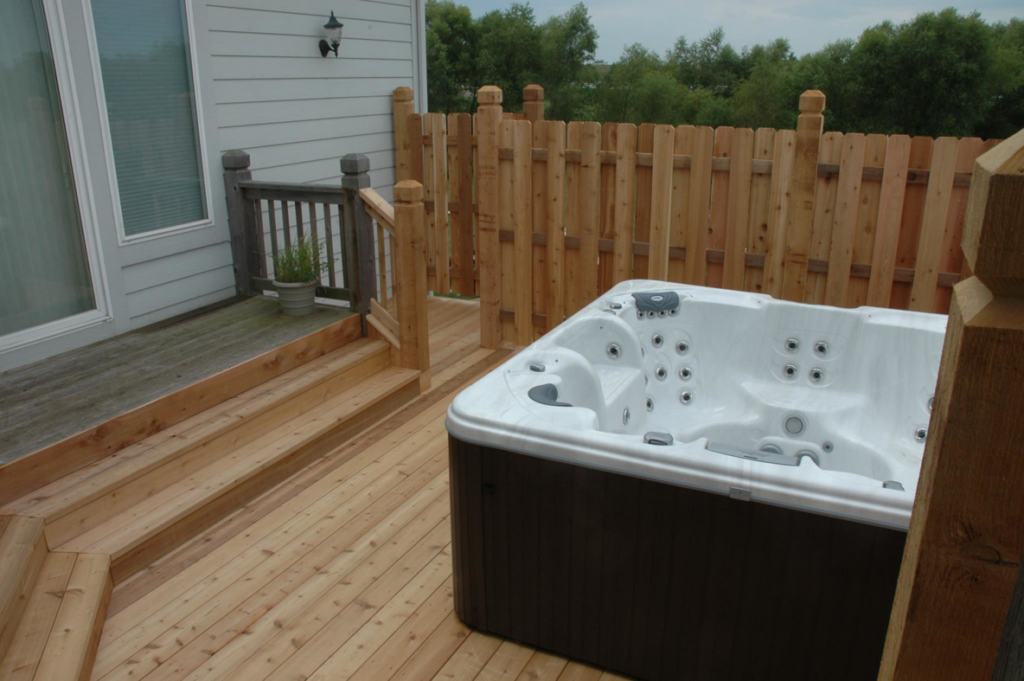 A wooden deck with a hot tub and custom stairs providing access to a home by Holm Remodeling Company in Kansas City, KS.