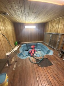 Indoor hot tub installation or removal in progress, with tools and hoses, handled by No Delay SVCS in Pocatello, ID.