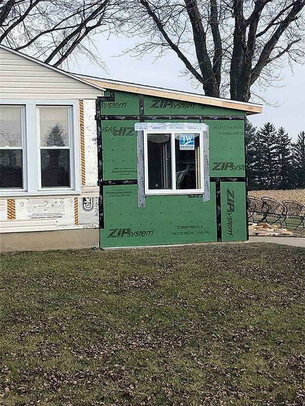 A residential house addition under construction with green sheathing and new window installation by Elk Building Services in Toledo, OH.