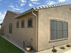 A house with dark sun screens installed on windows and a light-colored rain gutter, showcasing services by Phoenix Rain Gutters and Sun Protection in Glendale, AZ.