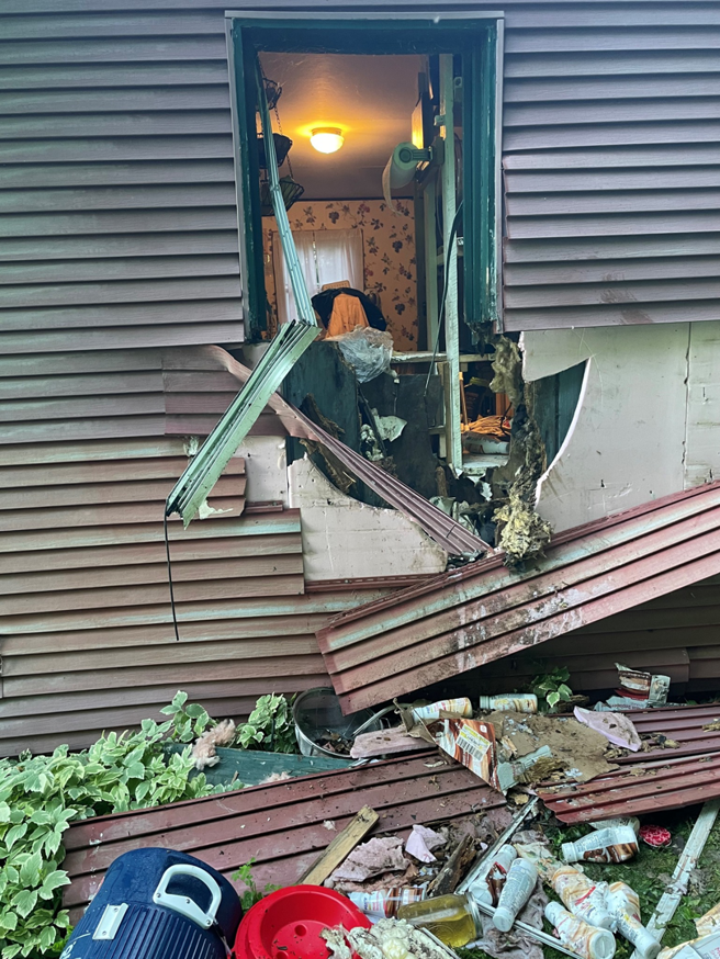 Debris from a damaged house, including broken siding and trash, requiring cleanup by Greater Upper Valley Solid Waste Management District in Ascutney, VT.
