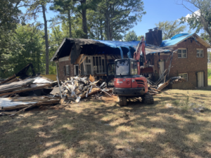 An excavator demolishing a house and removing debris for Green Brothers Services in Harvest, AL