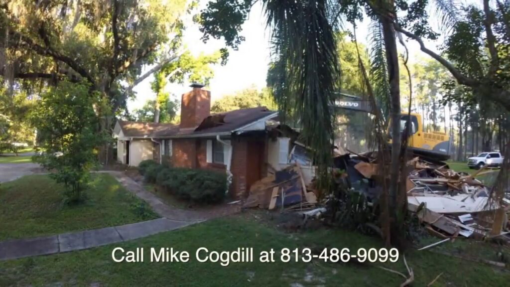 A house undergoing demolition with an excavator in the background, managed by Cogdill Builders of Florida in Tampa, FL.