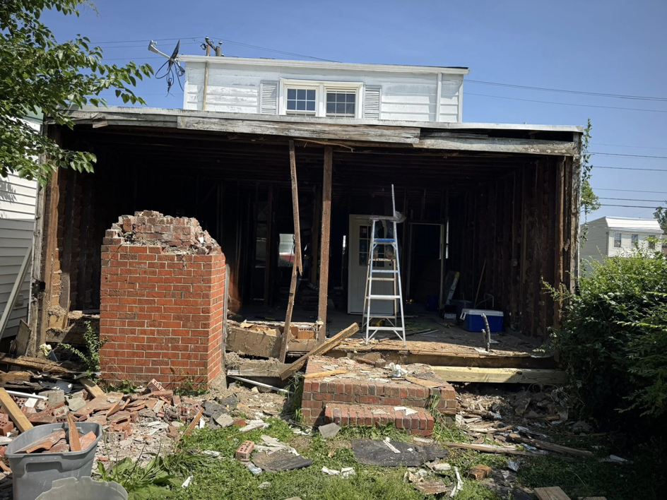 Exterior view of a house undergoing demolition and renovation, showing exposed framing and debris by Staley Contracting in Richmond, VA