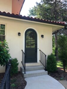 A stylish house entrance with an arched black door and new railings by Creasey Construction of Illinois, Inc. in Springfield, IL