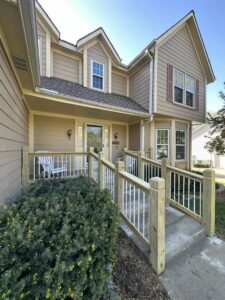 A house entrance with a newly installed wooden accessibility ramp and railings by Deckscape KC in Kansas City, MO.