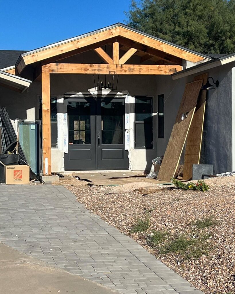 A house entrance under construction, featuring new double doors and a wooden porch structure by Kelso Custom Builders, Inc. in Phoenix, AZ.