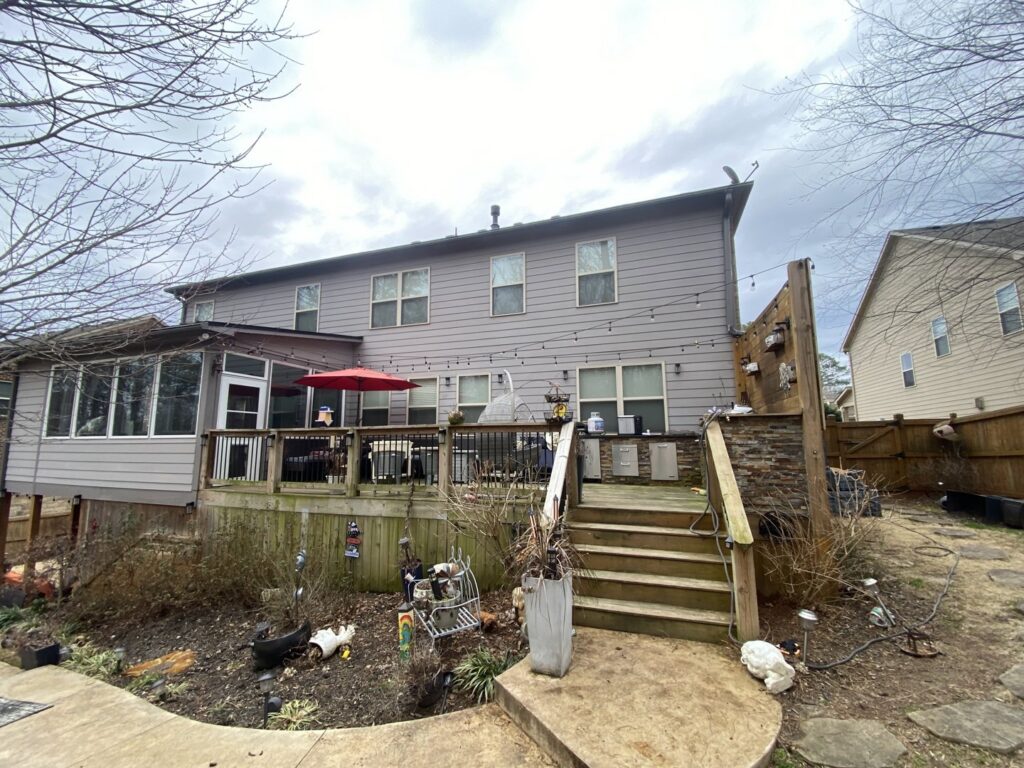The exterior of a house with a large wooden deck, showcasing a renovation project by Stonehedge Construction in Buford, GA