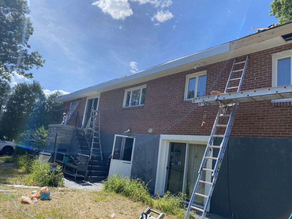 The exterior of a house with ladders and scaffolding set up, indicating ongoing exterior renovation or repair work by Home pro handyman llc in Olathe, KS