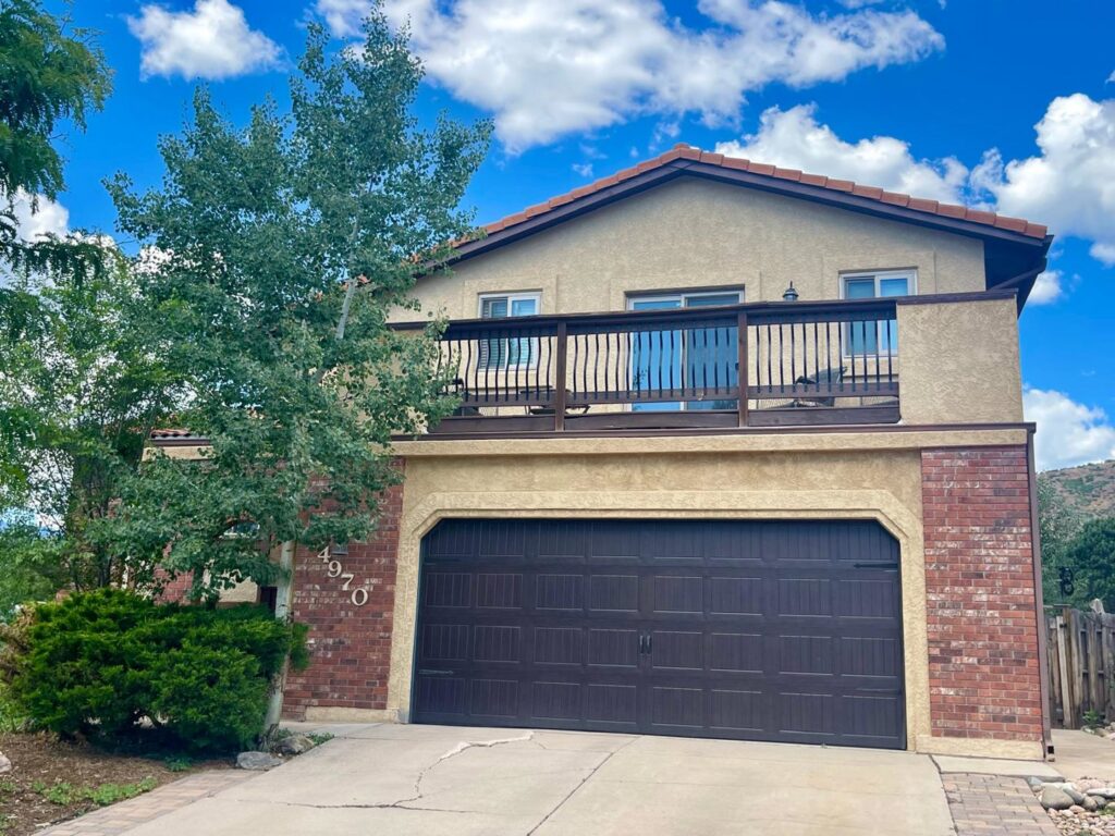 A house exterior featuring a large garage and a second-story balcony by Greg Unseth Painting & Exteriors in Colorado Springs, CO