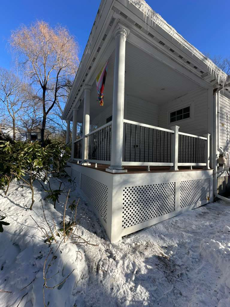 The exterior of a house featuring a newly built deck with white lattice skirting, completed by Remodel or Renew Home Improvement in Worcester, MA.