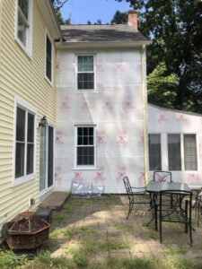 The exterior of a house with new house wrap installed on a section of the wall, demonstrating a home improvement service by Home pro handyman llc in Olathe, KS