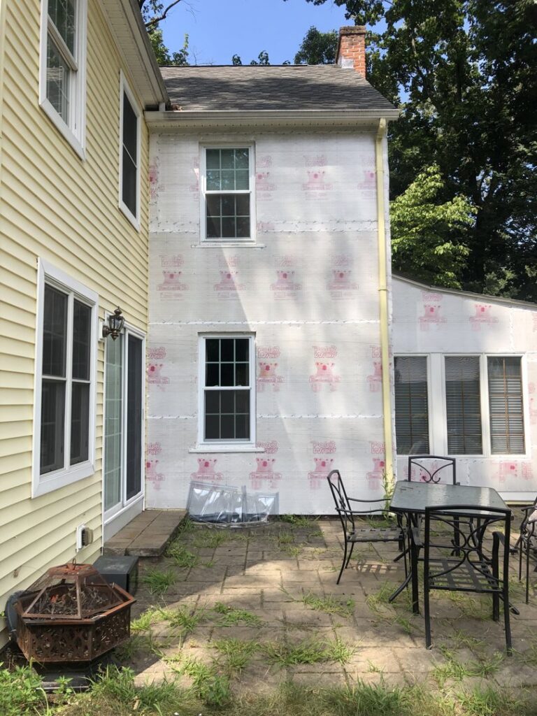 The exterior of a house with new house wrap installed on a section of the wall, demonstrating a home improvement service by Home pro handyman llc in Olathe, KS