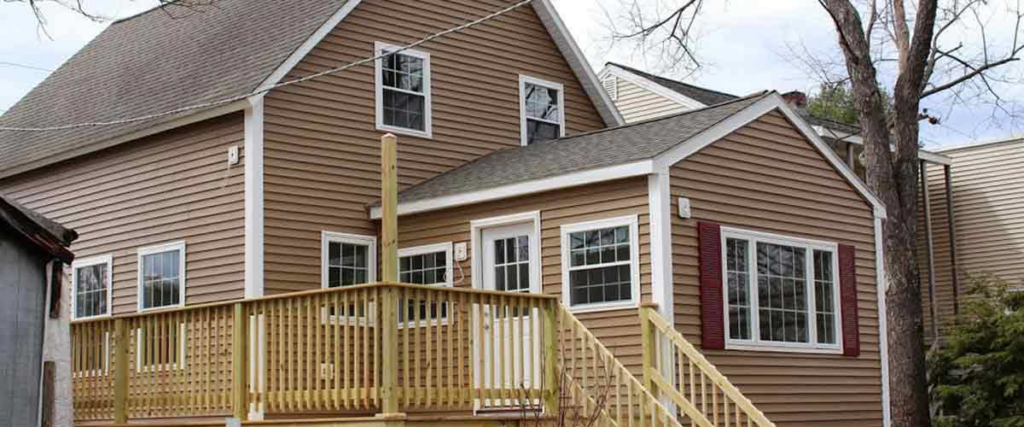 A house exterior with newly installed siding and a wooden deck, showcasing handyman work by Rescuereo.com LLC in Worcester, MA.