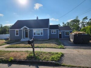A house exterior with newly installed siding and a construction dumpster, indicating renovation work by Santoro Home Improvements in Wallingford, CT.