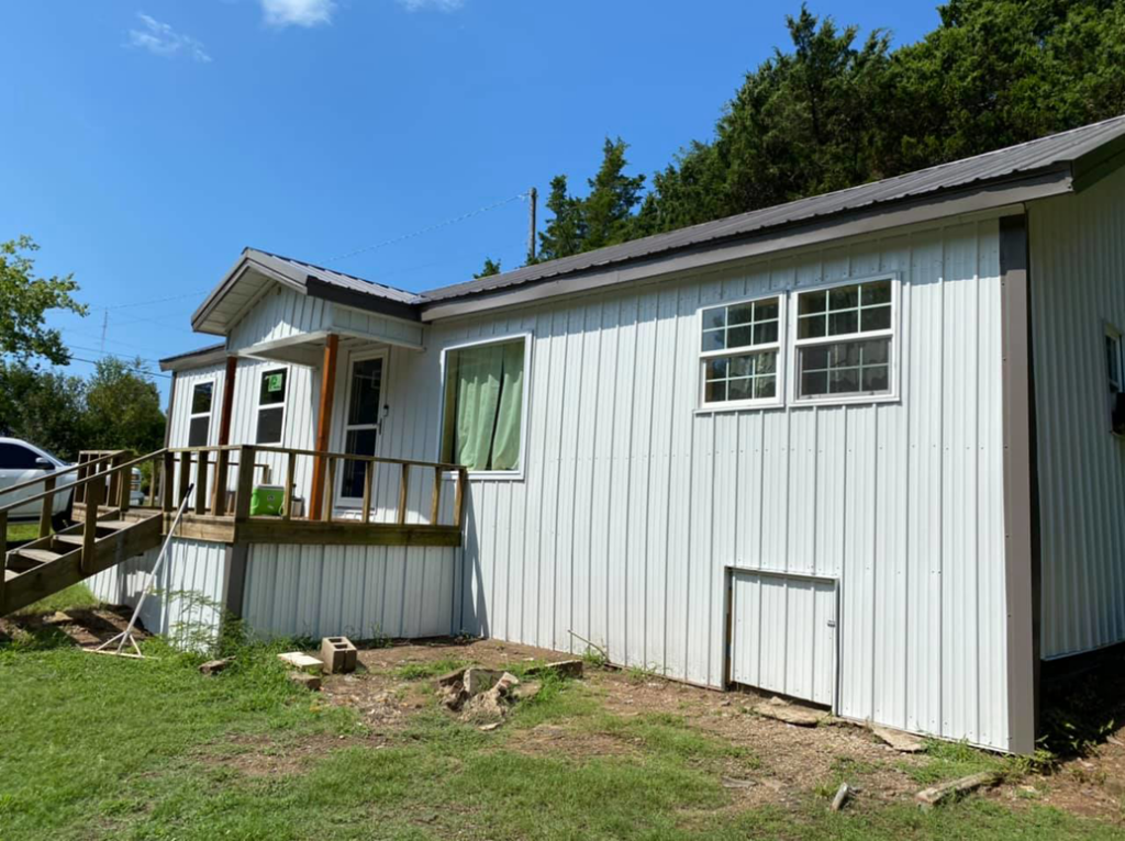 The exterior of a house featuring new metal siding, windows, and a wooden deck by Sterling Renovations in Grapevine, TX.