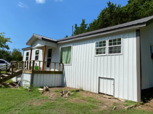 The exterior of a house featuring new metal siding, windows, and a wooden deck by Sterling Renovations in Grapevine, TX.