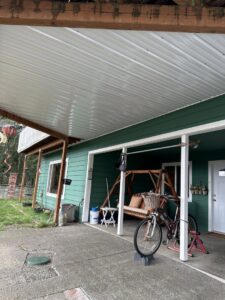 A house exterior with light brown siding and a wooden front door, freshly painted by Brush N' Roll Painting Co. in Federal Way, WA.