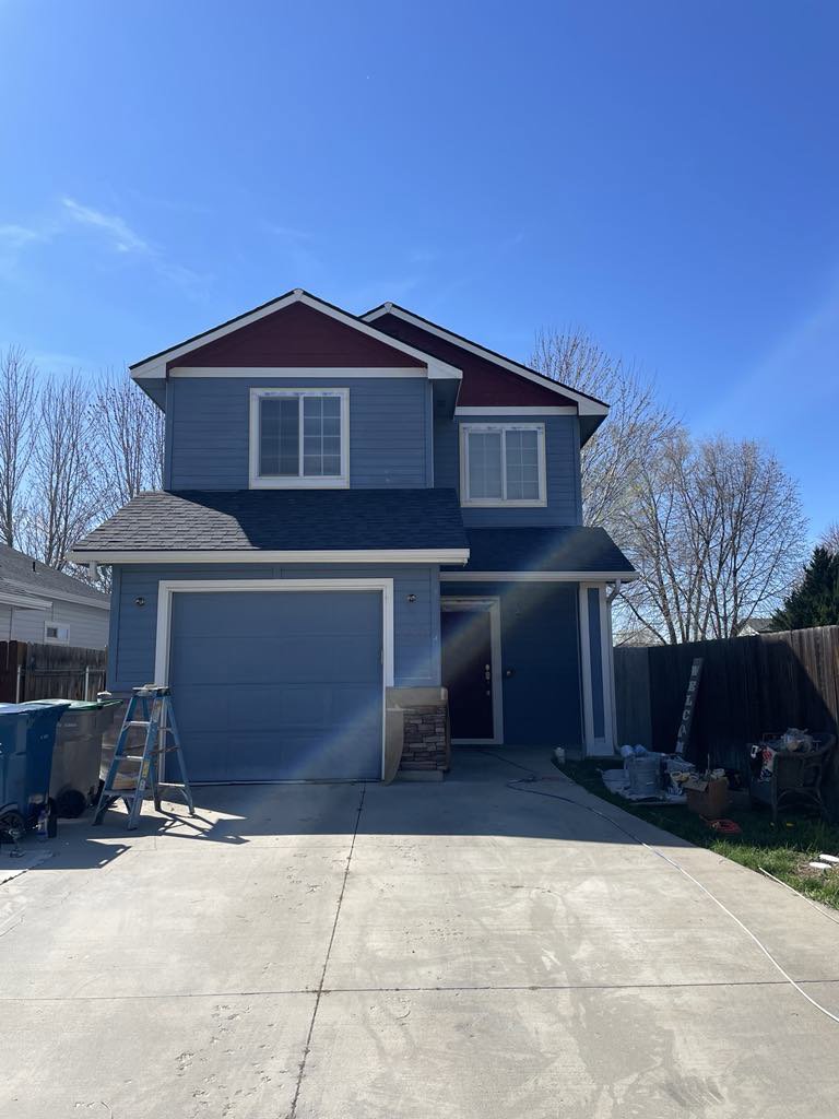 A newly painted blue house with red roof trim and a new garage door, showcasing exterior services by FES handyman services LLC in Boise, ID.