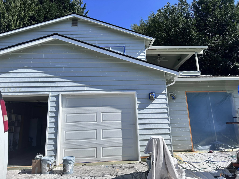 House exterior prepped for painting with buckets and protective tarps by J&R Buezo Painting Services LLC in Everett, WA