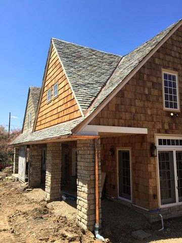 A residential house undergoing exterior renovation, featuring new siding, roofing, and stone veneer by Prescott Roofing and Masonry in Carnegie, PA.