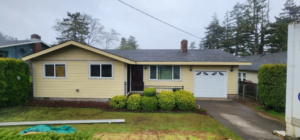A newly renovated house exterior with yellow siding and new windows by CJ Hansen Construction in North Bend, OR.