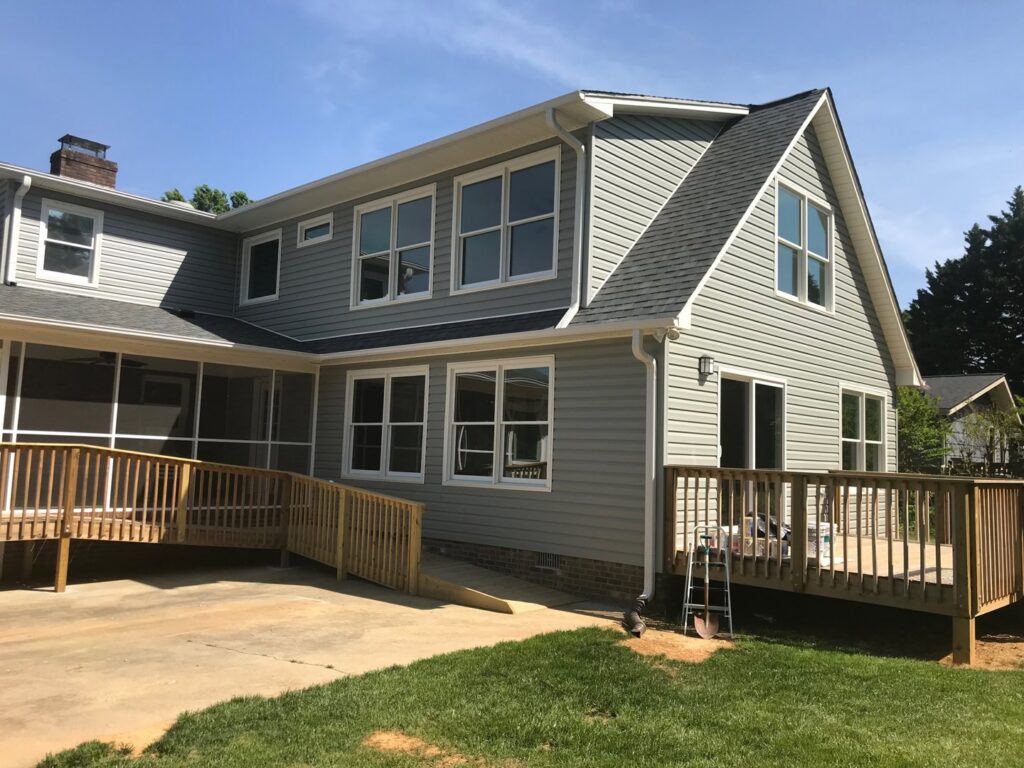 House exterior with new gray siding, windows, and a wooden deck with ramp by KC's Improvement & Construction Co., Inc. in Greensboro, NC