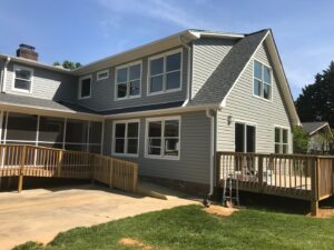 House exterior with new gray siding, windows, and a wooden deck with ramp by KC's Improvement & Construction Co., Inc. in Greensboro, NC