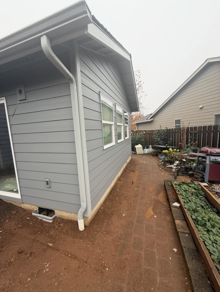 House exterior with new gray siding and white gutters installed by Reborn Construction LLC in Wilsonville, OR.