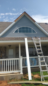 New blue siding being installed on a house exterior with a ladder and materials by Barrios Remodeling in Kansas City, MO.