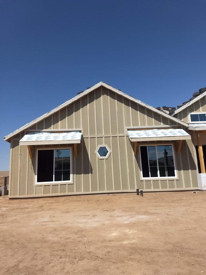 The exterior of a house under construction with vertical siding and new windows by AZ Framing and Remodeling in Peoria, AZ