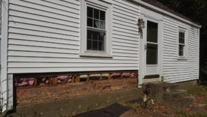 Exterior view of a house showing damaged lower wall section requiring repair by DiBenedetto Building & Remodeling in Worcester, MA.