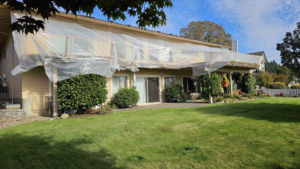 A house exterior covered in plastic sheeting for waterproofing or repair by Titan Exteriors in Hillsboro, OR.