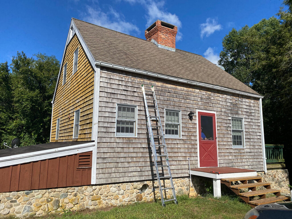 A house exterior with wooden shingle siding and a ladder, indicating handyman work by GO Painting in New Haven, CT