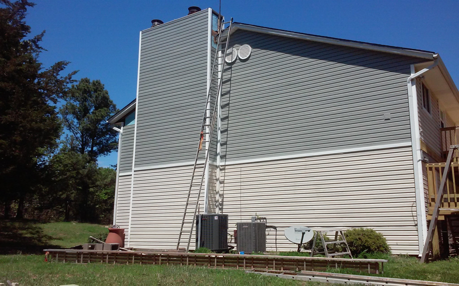 The side of a house with new grey and white siding, a chimney, and a ladder at Hurst Siding Co. in Norman, OK