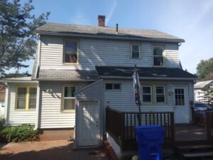 The exterior of a house featuring yellow window frames and light-colored siding by Brothers Home Improvement in East Hartford, CT