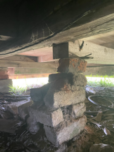 A stack of bricks supporting a wooden beam under a house, showing foundation repair by LA Pro Land Services llc in Houma, LA