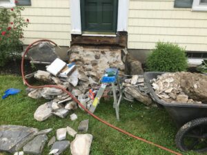 House foundation and steps undergoing repair, with debris and tools visible, by Sini's Handyman Services in Falmouth, ME.