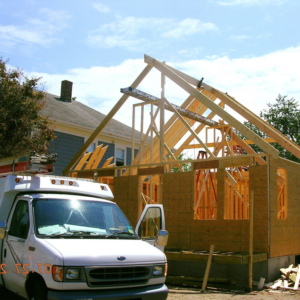 A house under construction with visible wood framing and a work van by Hammer & Nail Construction in Cumberland, RI.