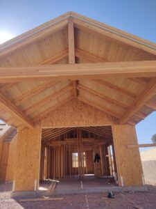 Front of a house under construction, showing wood framing for garage and entrance by AZ Framing and Remodeling in Peoria, AZ