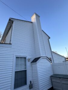 Exterior of a house with new white siding and a renovated chimney by Universal Builders LLC in New Haven, CT.