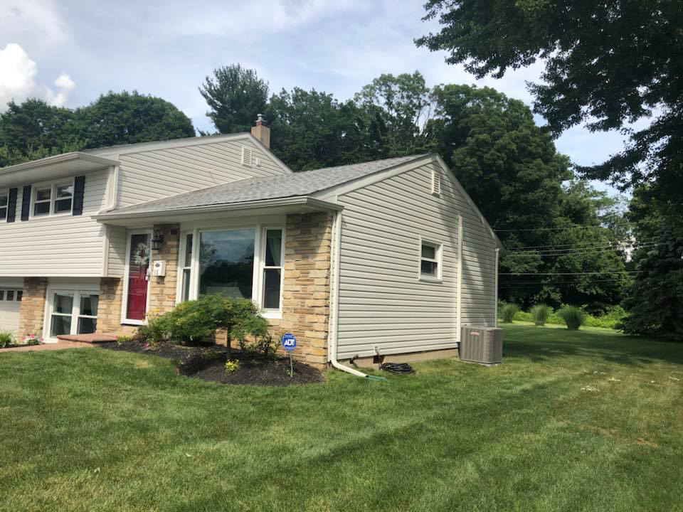A house with newly installed siding and stone veneer on the front and side, completed by Quality Care Home Improvements in Hamilton, NJ.