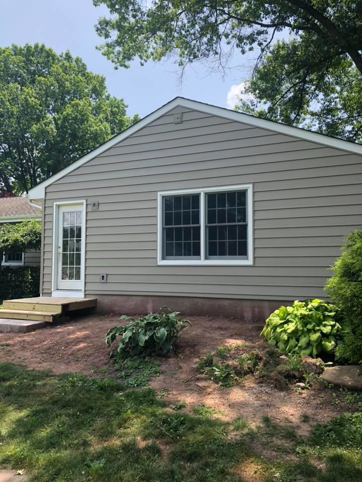 The side of a house featuring new siding, a new window, and a new back door with steps, completed by Quality Care Home Improvements in Hamilton, NJ.
